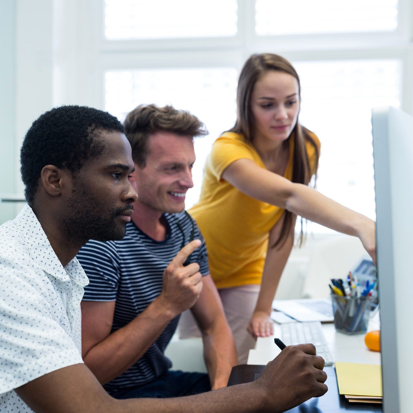 Male and female graphic designers using graphics tablet in office